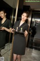 A woman in a black dress holding a tray of perfume.