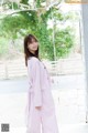 A woman in a pink coat standing in front of a gate.