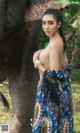 A woman standing next to an elephant in a forest.