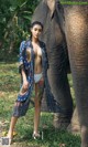 A woman standing next to an elephant in a forest.