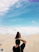 A man and a woman sitting on top of a sand dune.