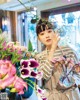 A woman holding a vase of flowers in front of her face.