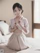 A woman in a white kimono sitting on a bed.