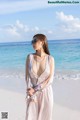 A woman standing on a beach next to the ocean.