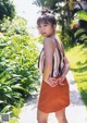 A woman in a striped top and orange skirt posing for a picture.