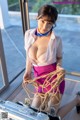 A woman in a white shirt and pink skirt holding a rope.