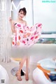 A woman in a pink dress posing in front of a window.