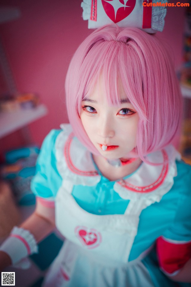A woman with pink hair wearing a blue and white dress.