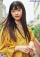 A woman in a yellow dress posing for a picture.