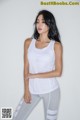 A woman in a white tank top and gray leggings.