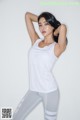 A woman in a white tank top and gray leggings posing for a picture.
