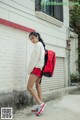 A woman with a red backpack is walking down the street.