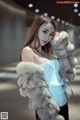 A woman in a blue top and fur coat posing for a picture.
