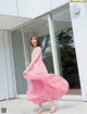 A woman in a pink dress is walking outside of a building.