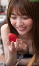 A woman holding a strawberry in her hand.