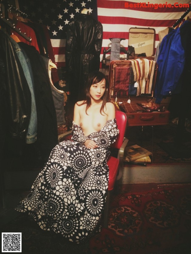A woman sitting in a chair in front of an American flag.