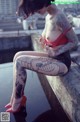 A woman with tattoos sitting on a ledge.